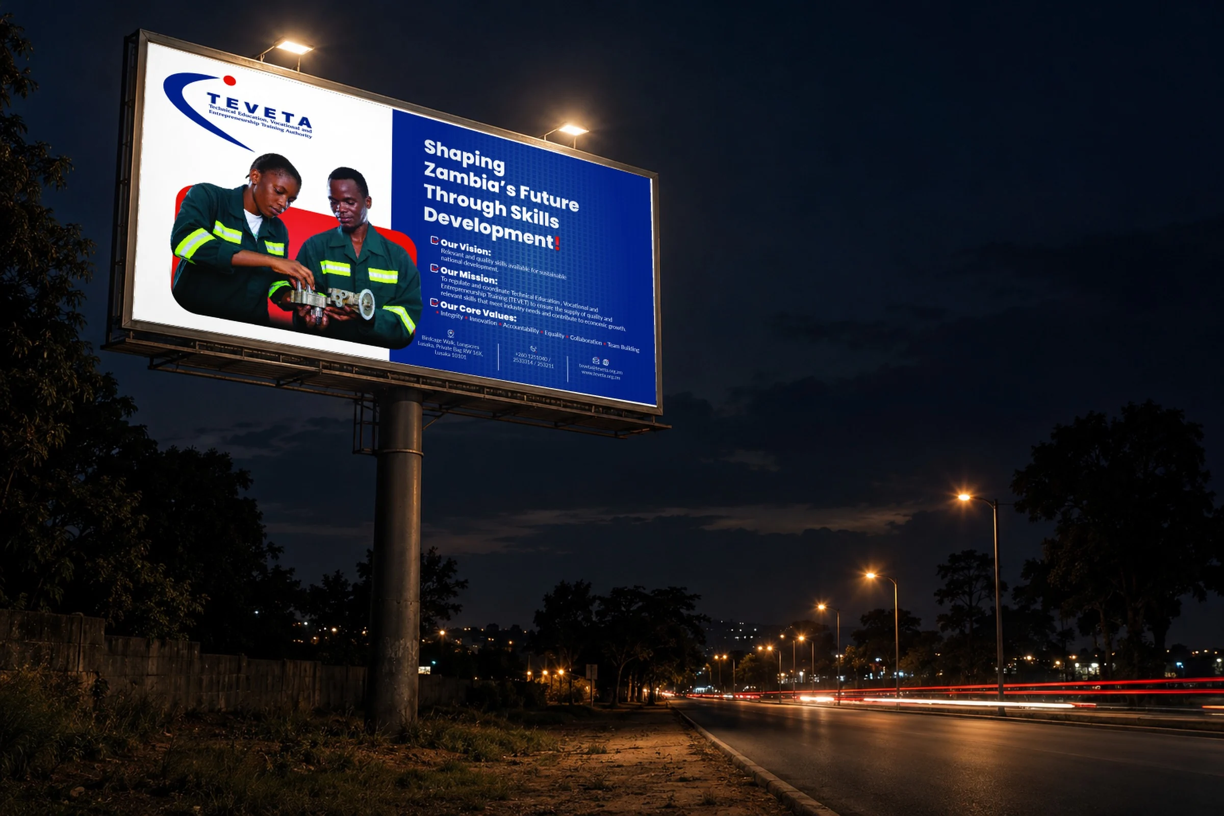 The TEVETA billboard Shaping Zambia's Future Through Skills Development, lit at night beside a road
