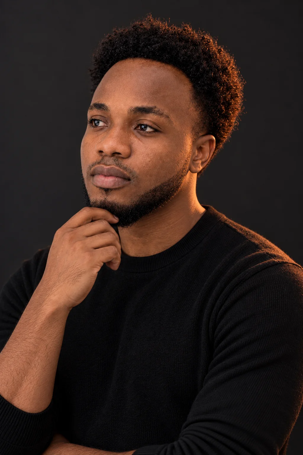 Three-quarter profile in the studio, hand at his chin, looking away in thought